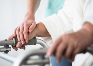 nurse helping to guide a resident using a walker